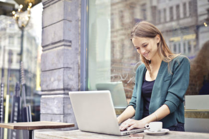 Business woman on laptop outside with coffee