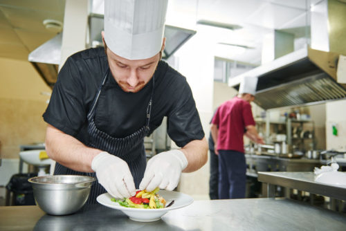 Male cook decorating dish